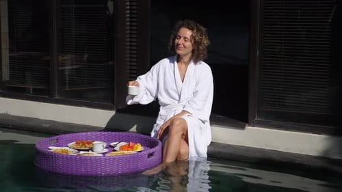 The Young Curly Caucasian Woman Starts Her Day with a Coffee and Breakfast From the Floating Tray at