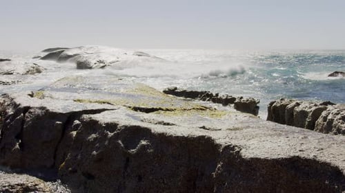 Pedestal Shot of Big Waves Hitting a Rocky Coastline on a Summer Day