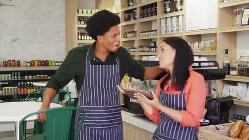 Video of happy diverse female and male waiters in aprons at coffee shop