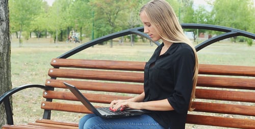 Woman Works on Laptop in Sunny Park
