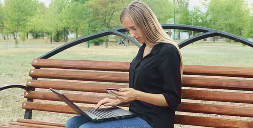 Beautiful Girl Uses Online Banking in the Park