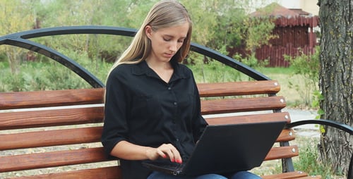 Young Girl Resting in a Park and Using Laptop