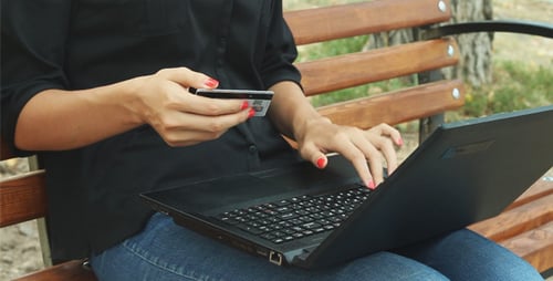 Woman Using Laptop with Credit Card on Bench