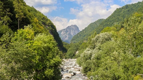Wolken über Berggipfel und Fluss im Piemont