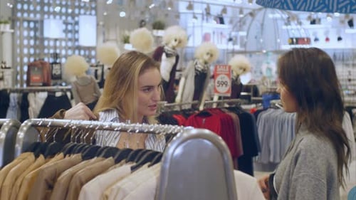 Bonita morena eligiendo y probándose una chaqueta con un amigo en el centro comercial