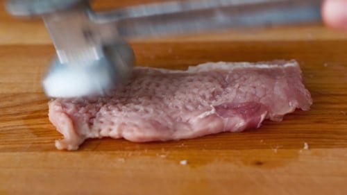 Tenderizing Pork Meat on Wooden Cutting Board