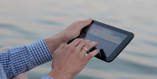 Close Up Hands Using Tablet Device by Water