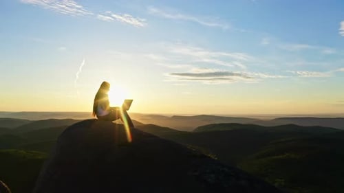Woman Works on Laptop at Sunrise in Mountains