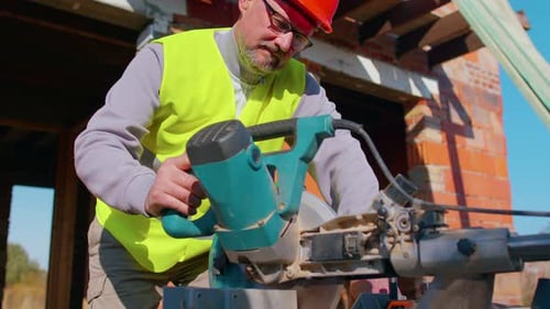 Construction Worker Using Saw to Cut Wood