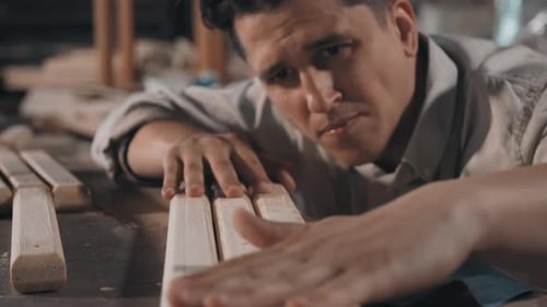 Man Sands Wood Beams in Workshop