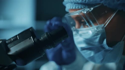 Medical Researcher Works with Microscope in Laboratory