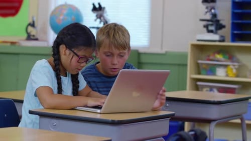 Two kids in school classroom working on laptop computer