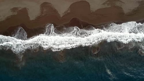 Wellen schlagen vor einem abgelegenen Strand aus der Vogelperspektive