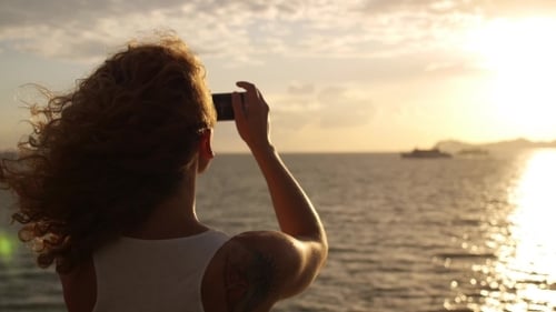 Woman Captures Golden Sunrise over Ocean with Phone