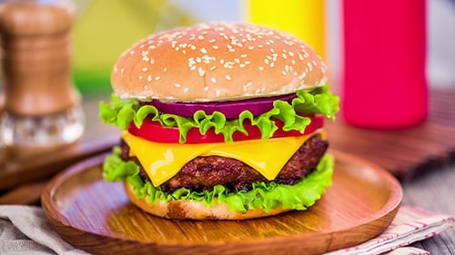 Delicious Cheeseburger with Fresh Toppings on Wooden Plate
