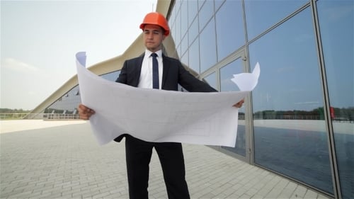 Architect Examining Blueprints Outside Modern Building