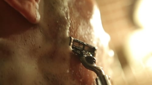 Homem branco barbeando com uma navalha