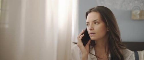 Close up of a woman talking to someone on the phone, near the window
