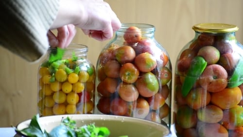 Woman Lays Tomatoes And Cucumbers In Jars. Home
