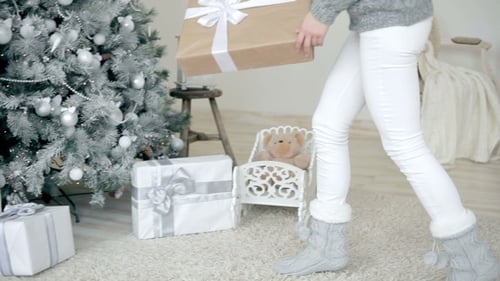 Woman Places Gift Under a Christmas Tree