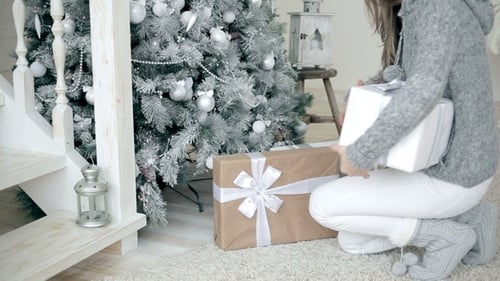 Woman Arranging Christmas Presents Under Decorated Tree