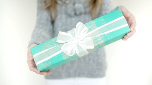 Holding Out Turquoise Gift with White Ribbon