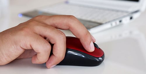 Hand Clicking a Wireless Mouse Next to Laptop