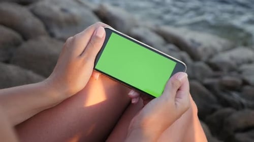 Mujer en cámara lenta sostiene un teléfono con pantalla verde junto al mar Imágenes HD de 1920X1080 - Dispositivo de pantalla verde en f