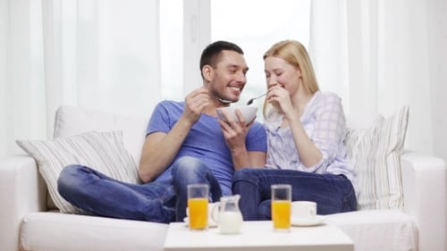 Happy Couple Sharing Cereal in Bright Living Room