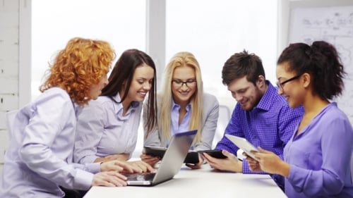 Equipe sorridente com computadores portáteis e de mesa