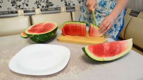 Woman Slicing a Fresh Watermelon on a Table