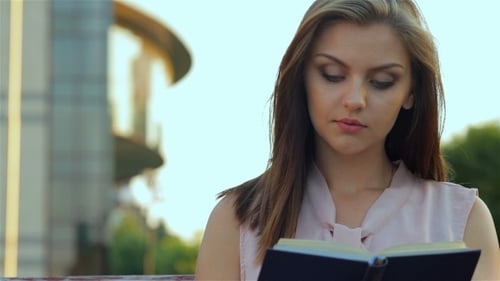 Young Woman Reading Book Outdoors