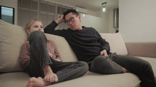 Adult and Child Relaxing on Couch Watching TV