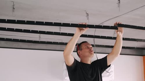 Trabalhador instalando acessórios para teto suspenso de metal