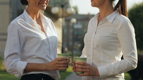 Two Women Talking in Urban Park with Coffee