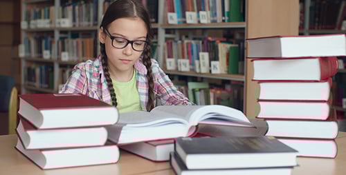 Girl Studies with Books in School Library
