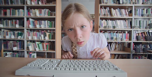 Young Girl Types on Keyboard in Library