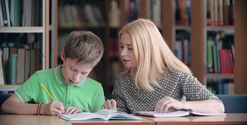 Woman Tutoring Boy in Library