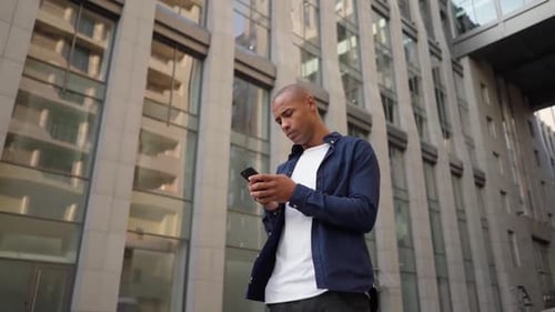 Man Standing on City Street and Answering a Call
