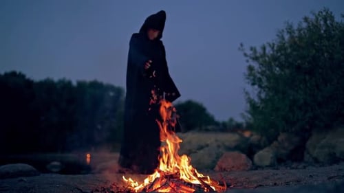 Hooded Figure by Campfire at Night