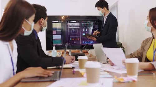 Young people with face masks back at work in office after lockdown.Asian small business startup