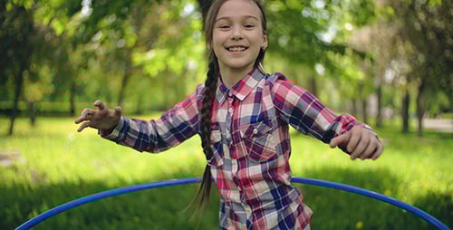 Smiling Girl Hula Hooping in Green Park on Sunny Day