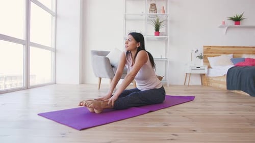 Woman Stretching on Yoga Mat in Bedroom