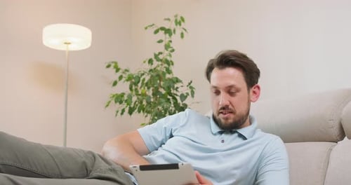 Man Relaxing on Couch with Tablet Indoors