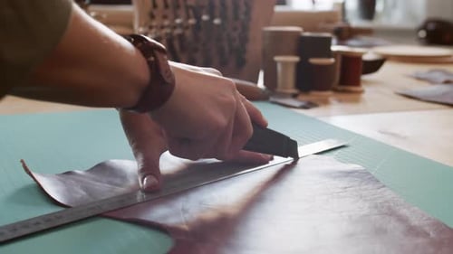 Hands Cutting Leather with Ruler and Cutter