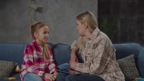 Mother and Daughter Conversing on Sofa with Tablet