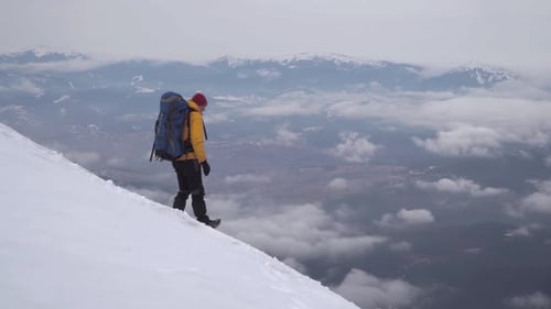 Man Hiking Across Snow Covered Mountain in Winter