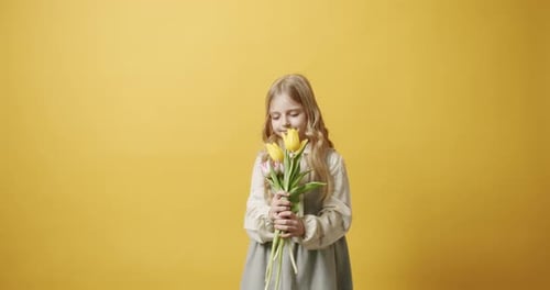 Girl Smelling Colorful Tulips Against Yellow Background