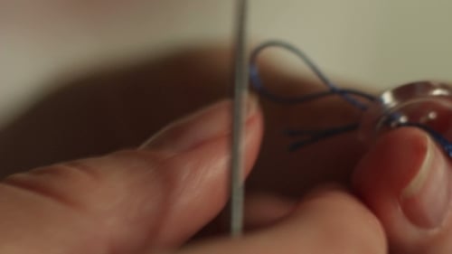 Hands Sewing Button with Needle and Thread