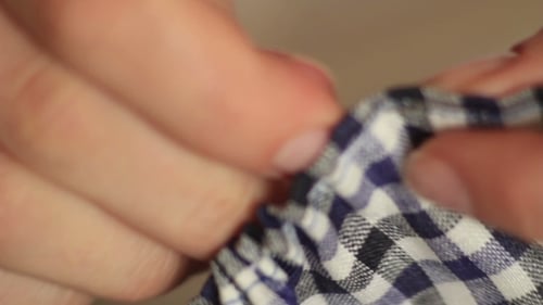 Close Up of Hands Sewing Checkered Fabric